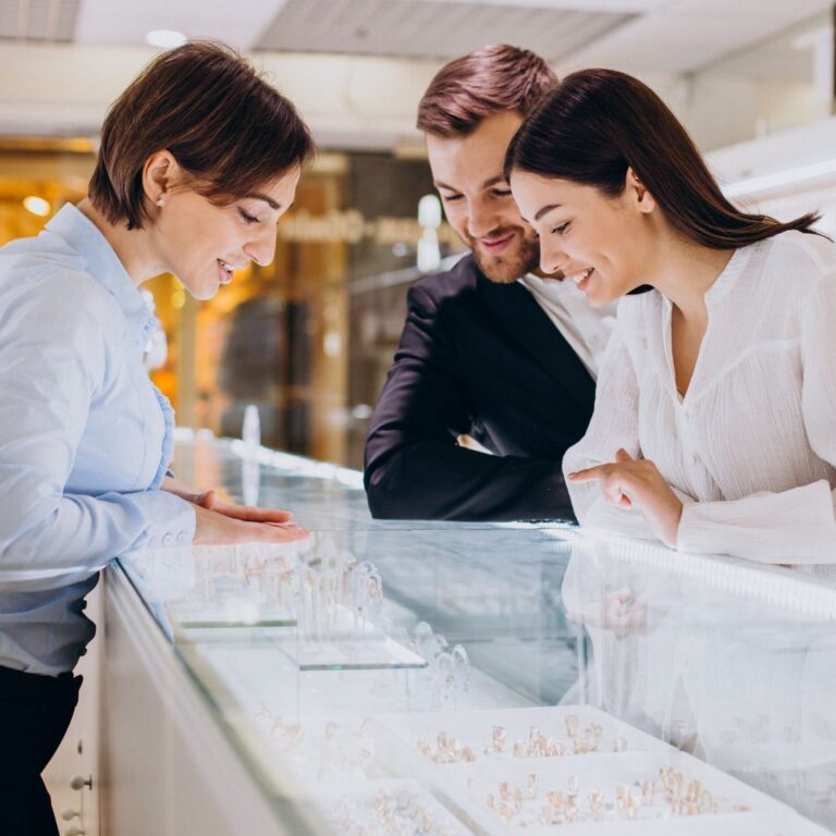 A couple acting as mystery shoppers engage in conversation with a salesperson at a jewelry store for a mystery audit for the brand.