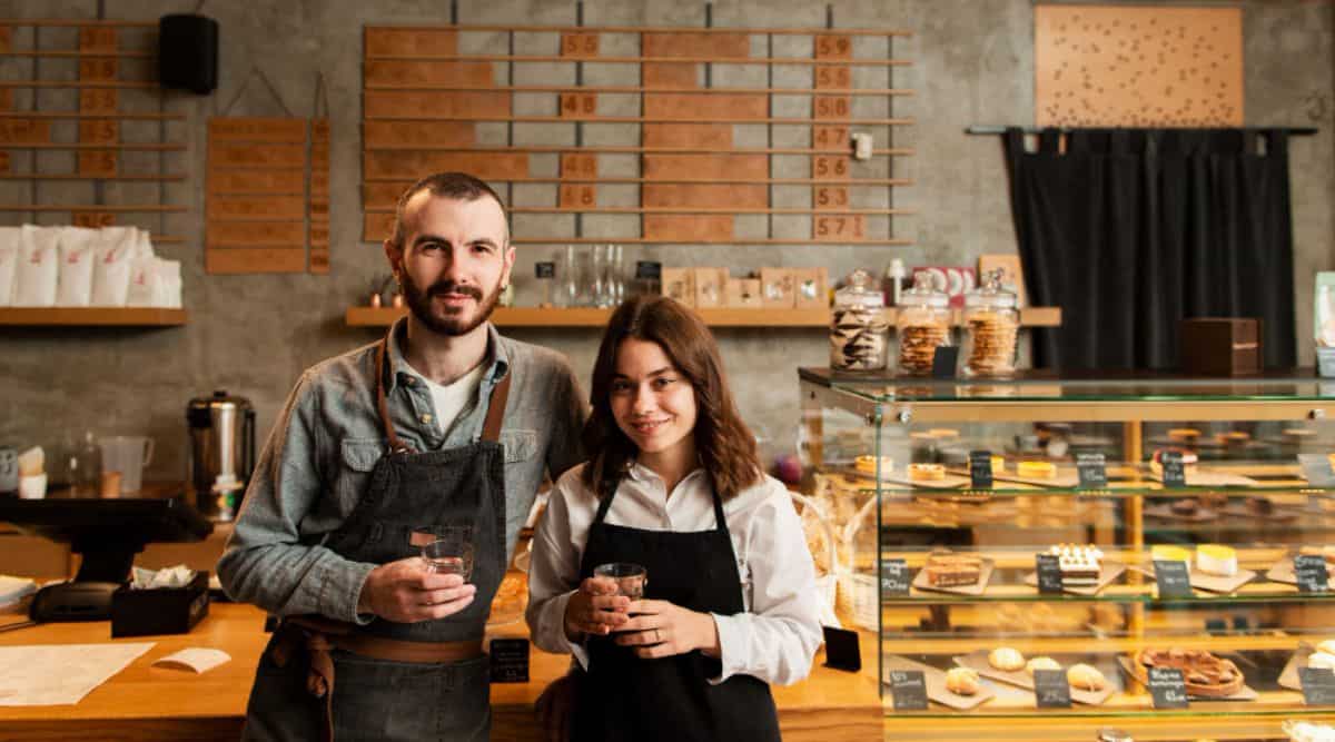 
A couple of entrepreneurs in aprons strike a pose with cups of coffee, having honed their offerings through diligent "Market Research for Small Businesses" to meet the discerning tastes of their customers.